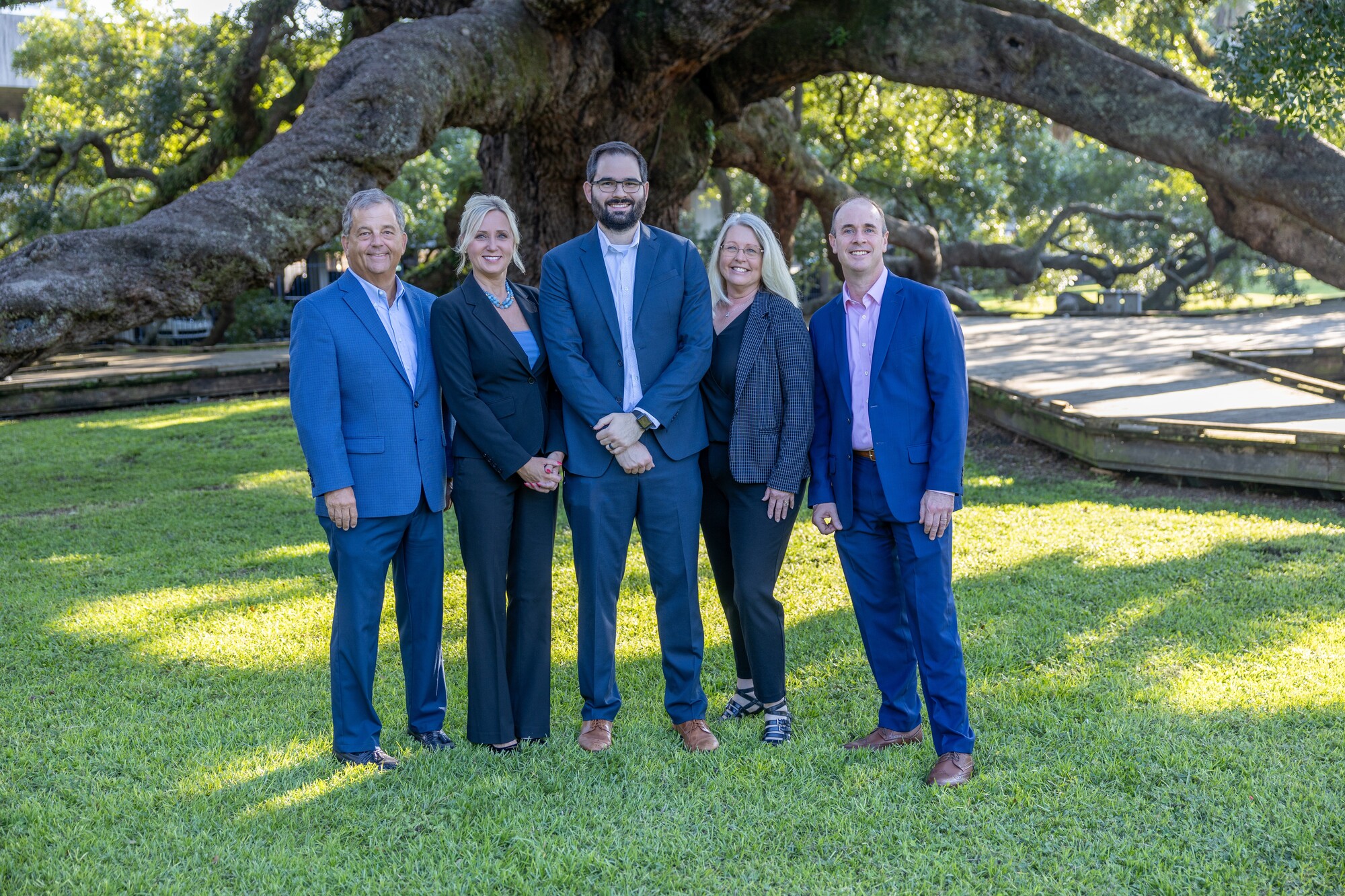 Photo of the Comprehensive Financial Consultants team wearing professional attire while standing in front of a large oak tree